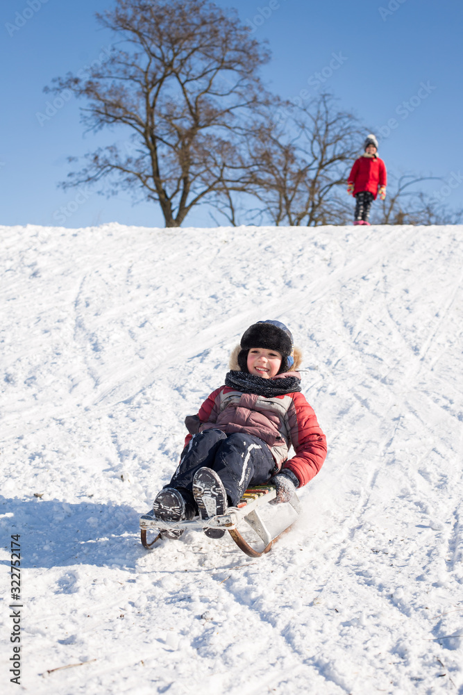 Children sledding downhill on a sunny frosty winter day