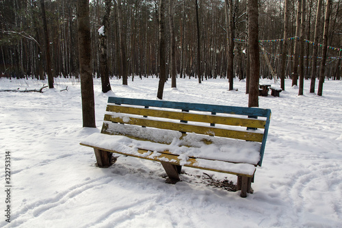 Bench in the park is covered in snow. Winter in the city