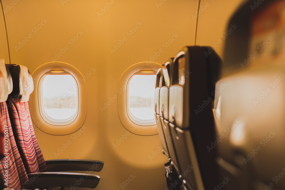 Empty airplane passenger seats next to window in economy class.