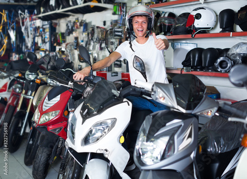 Cheerful man in helmet is sitting on motorbike satisfied by purc