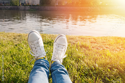 Close-up shot of woman's feet in white classic sneakers on the green grass