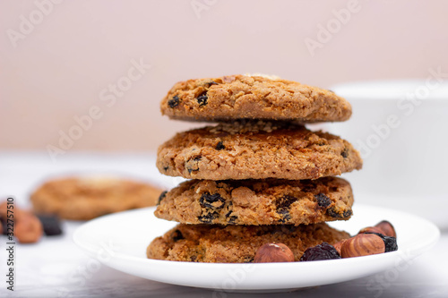 Fresh oatmeal friable cookies on a plate with nuts and raisins. The concept of a delicious and healthy breakfast.