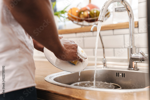 Guy in the morning at the kitchen wash the dishes.