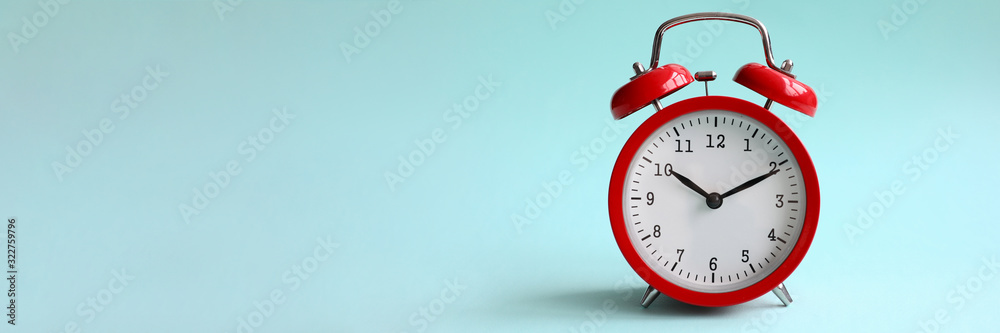 Red alarm clock on turquoise background shows 10 hours 10 minutes in evening or morning. Time to choice concept - obrazy, fototapety, plakaty 