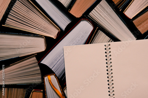 Lots of colourful thick open books stand on a dark background