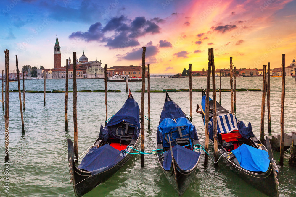 Venetian gondolas at the harbor and San Giorgio Maggiore island at sunset, Venice. Italy