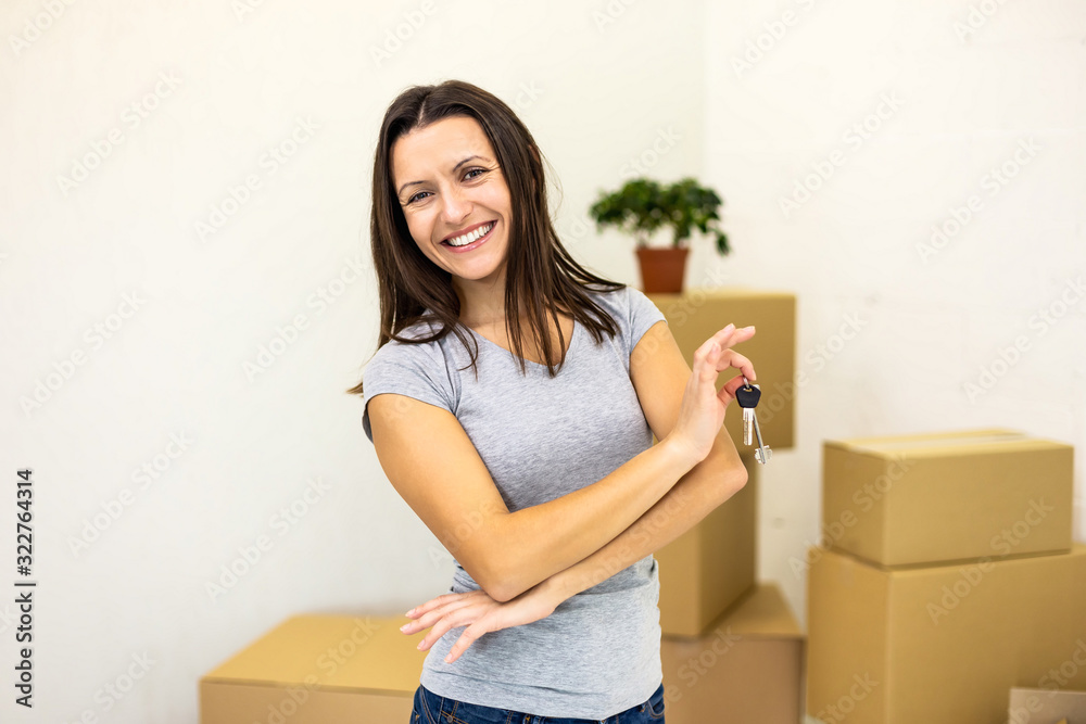 Female holding house keys on key chain and smiling to the camera with beaming smile. Concept for buying real estate. Female holding house keys on key chain and smiling to the camera with beaming smile. Concept for buying real estate.