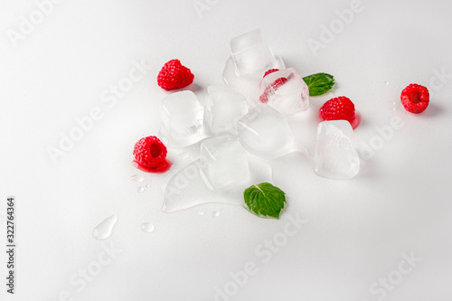 Fototapeta Naklejka Na Ścianę i Meble -  Ice cubes with raspberries and mint leaf on wooden table. Homemade skincare hydrating ice cubes. Close up, copy space for text