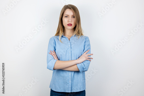 young blond serious woman looks resolute with her hands one one another standing on isolated white background