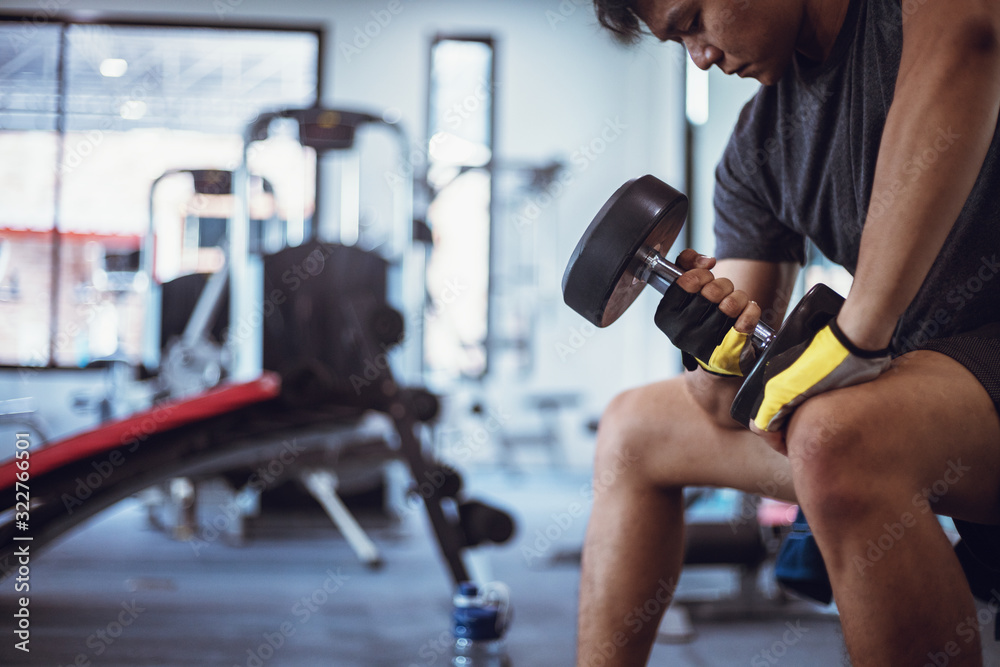 A man lifting dumbbells workouts with dumbbells in a gym. Sport man at fitness.