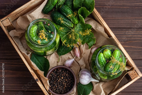Fermentation of cucumbers in glass jars. Raw cucumbers, dill flowers, cherry leaf, horseradish leaf, spices and herbs on a tray, concept of organic and healthy nutrition, pickling cucumbers.
