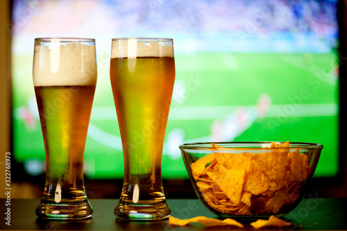 beer glasses and chips in front of tv - watching world cup football at home - soccer supporters