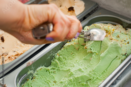 Woman dials a ball of ice cream. Scooping pistachio ice cream. Selective focus