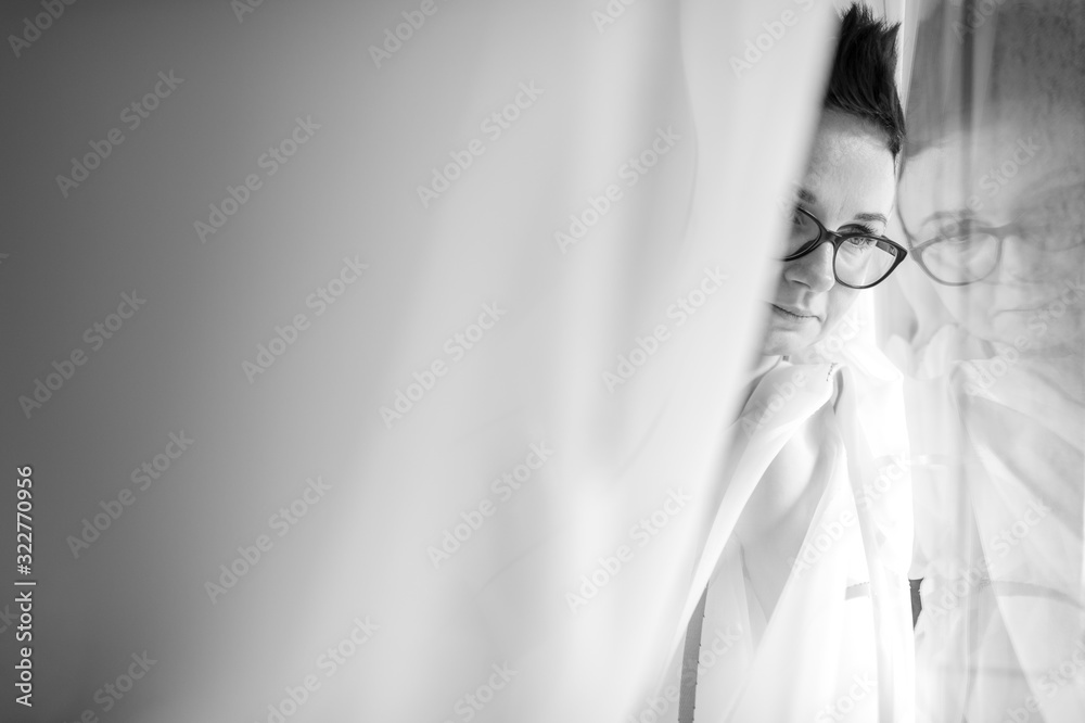 Beautiful woman with short haircut sits on the sofa and look out the window Beautiful woman with short haircut sits on the sofa and look out the window