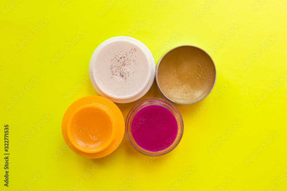 four tubes of colorful lip balms and lipsticks on a bright, clear yellow background. Ready-made layout for beauty salon and cosmetics advertising. Skin care in the cold season. four tubes of colorful lip balms and lipsticks on a bright, clear yellow background. Ready-made layout for beauty salon and cosmetics advertising. Skin care in the cold season.