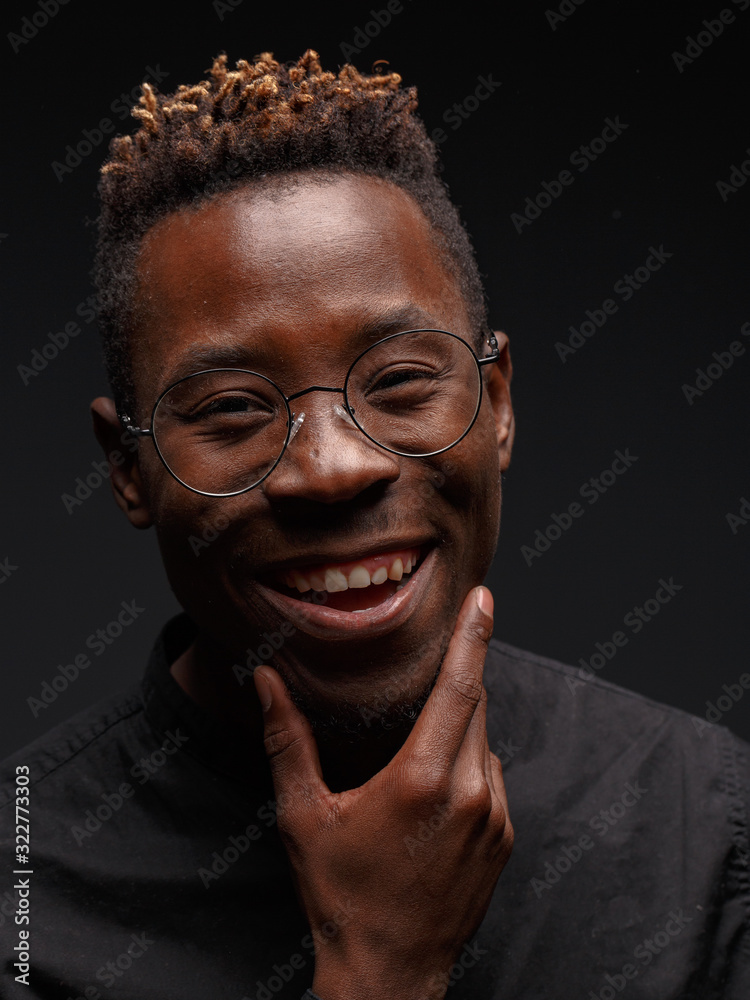 Emotional portrait of a young African man in black clothing against a dark background. Studio photography. Emotional portrait of a young African man in black clothing against a dark background. Studio photography.
