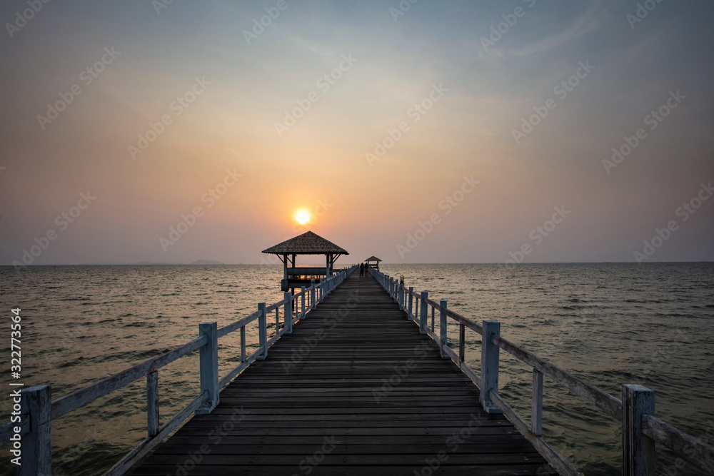 Sunset over white wooden pavilion and bridge over sea Sunset over white wooden pavilion and bridge over sea