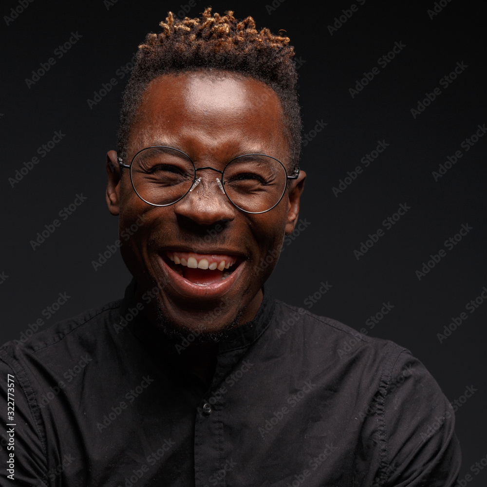 Emotional portrait of a young African man in black clothing against a dark background. Studio photography. Emotional portrait of a young African man in black clothing against a dark background. Studio photography.