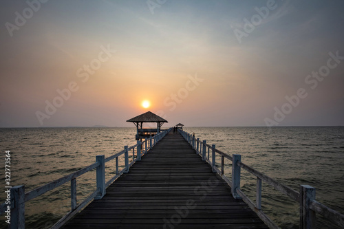 Sunset over white wooden pavilion and bridge over sea