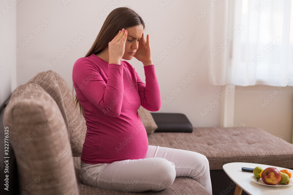 Pregnant woman having headache while spending time at her home. Pregnant woman having headache while spending time at her home.