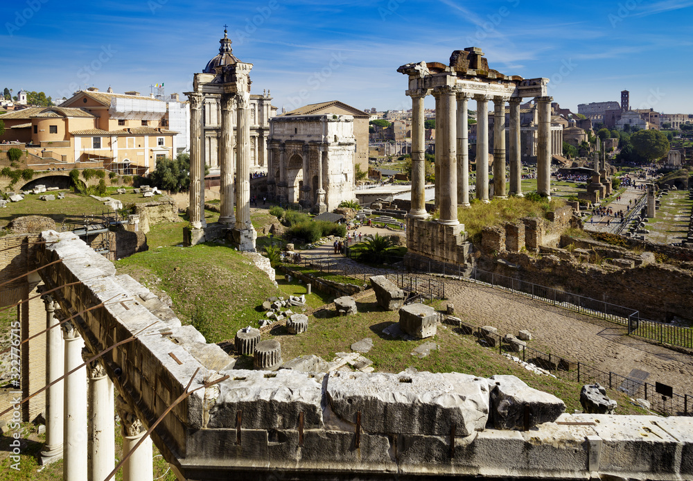 Ancient Roman Forum with blue sky and visible Colosseum in the far background in Rome, Italy