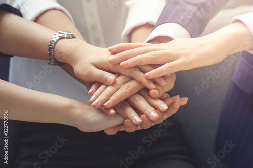 Group of businesswomen putting their hands together, unity and teamwork concept.