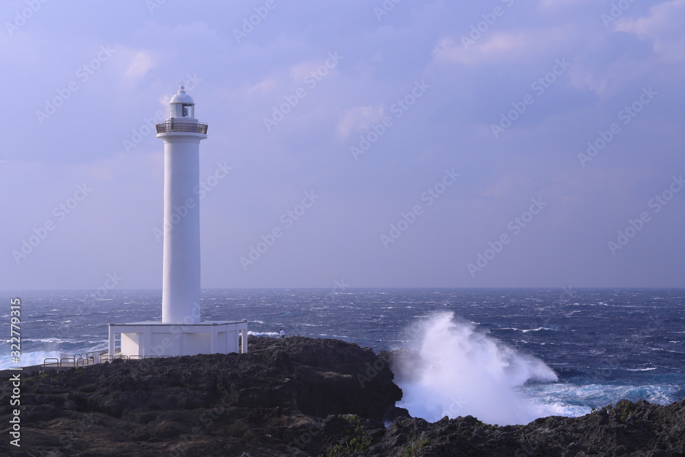 大波が押し寄せる岩壁に建つ灯台