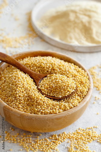 Hulled millet grain and flour in bowls photo