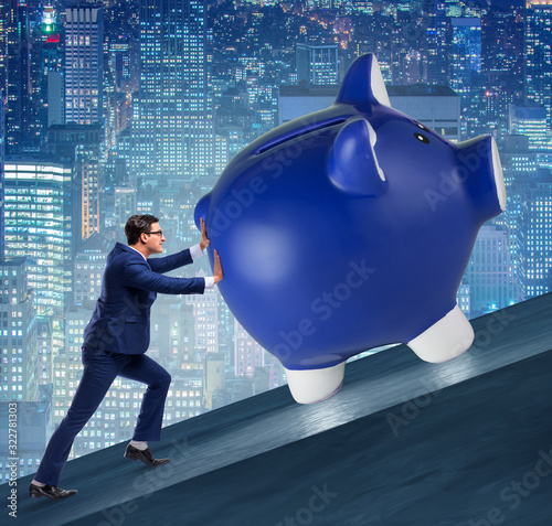 Foto Man pushing piggybank uphill in business concept
