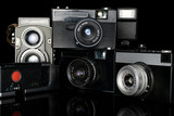 Group of five whole vintage camera isolated on black glass