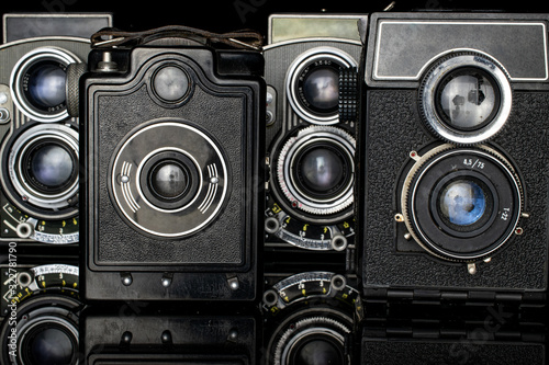 Group of four whole vintage camera isolated on black glass