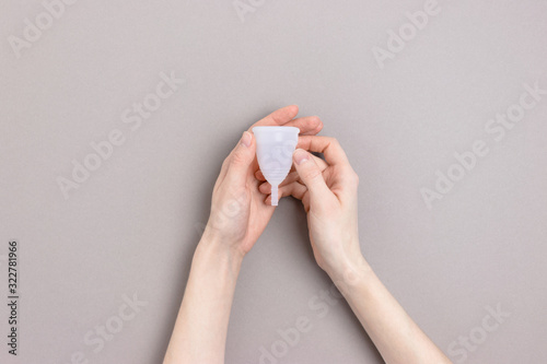 Hands hold menstrual cup. Minimalicstic zero waste concept on gray background.