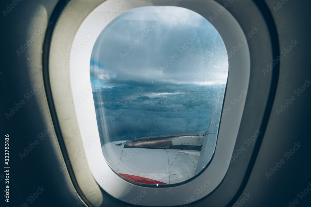 View from an airplane window, we fly above the clouds with a clear blue sky, we also see a piece of the wing and the engine of the plane View from an airplane window, we fly above the clouds with a clear blue sky, we also see a piece of the wing and the engine of the plane