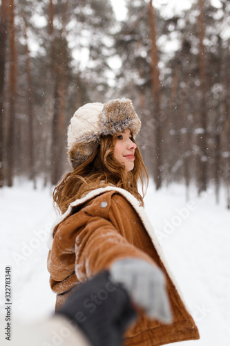 Happy lovers a guy and a girl who love each other hug, kiss, laugh, rage and walk in warm jackets in winter against the background of a snowy forest, a friendly family fun walk