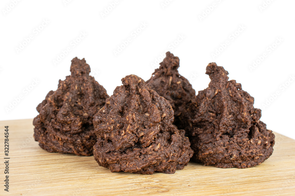 Group of four whole homemade brown coconut cocoa biscuit on bamboo cutting board isolated on white background