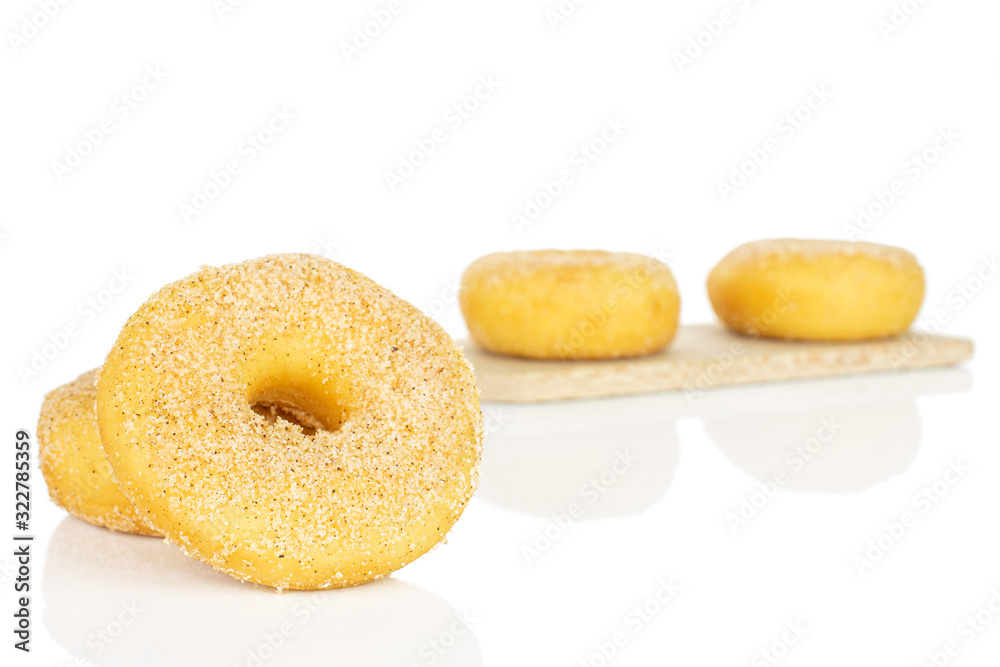 Group of four whole sweet golden mini cinnamon donut on small wooden cutting board isolated on white background Group of four whole sweet golden mini cinnamon donut on small wooden cutting board isolated on white background
