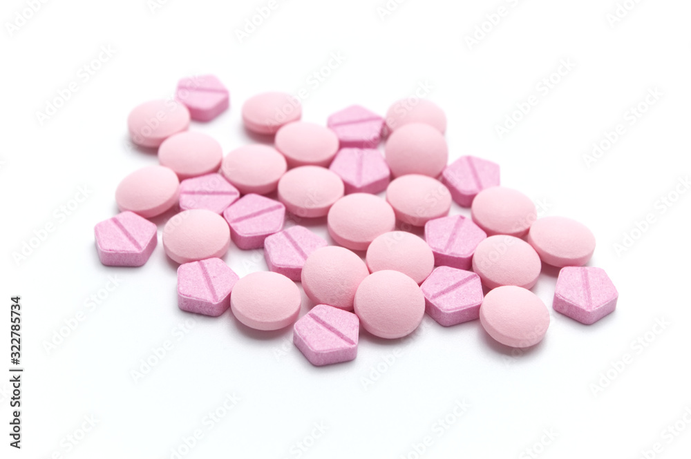 Prescription drugs or medicine pills and tablets of pink colors shades. On white background. Selective focus.