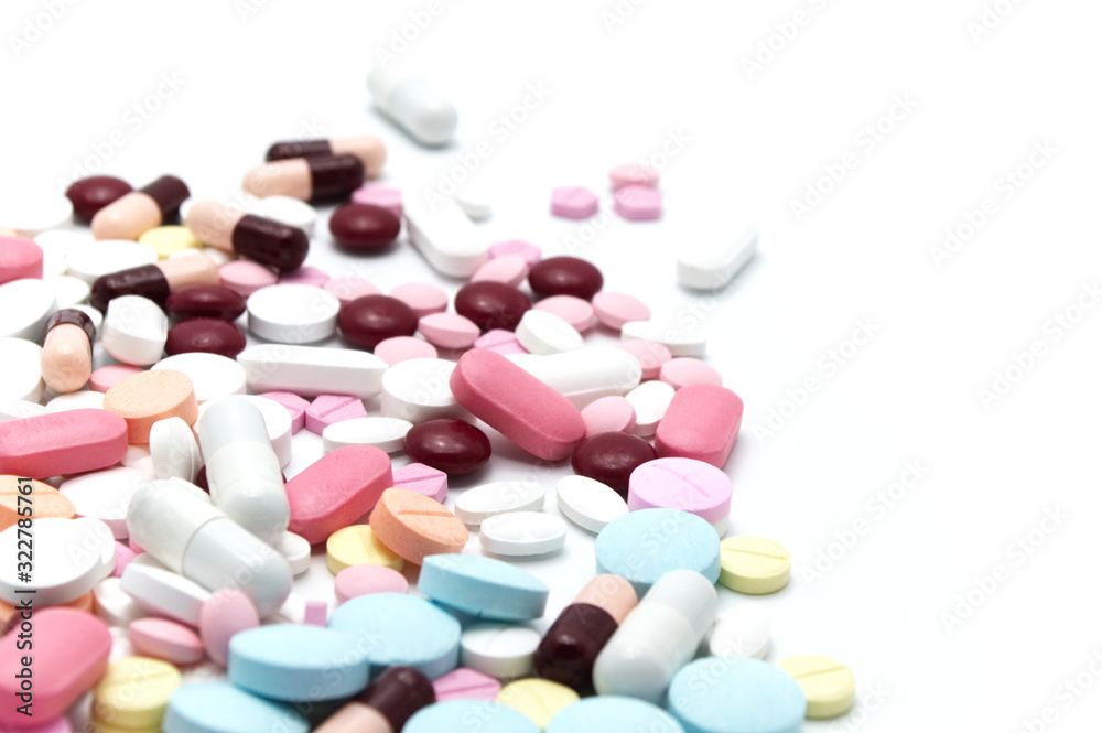 Prescription drugs, pills, capsules and tablets of different colors all mixed in. On white background. Selective focus. Prescription drugs, pills, capsules and tablets of different colors all mixed in. On white background. Selective focus.