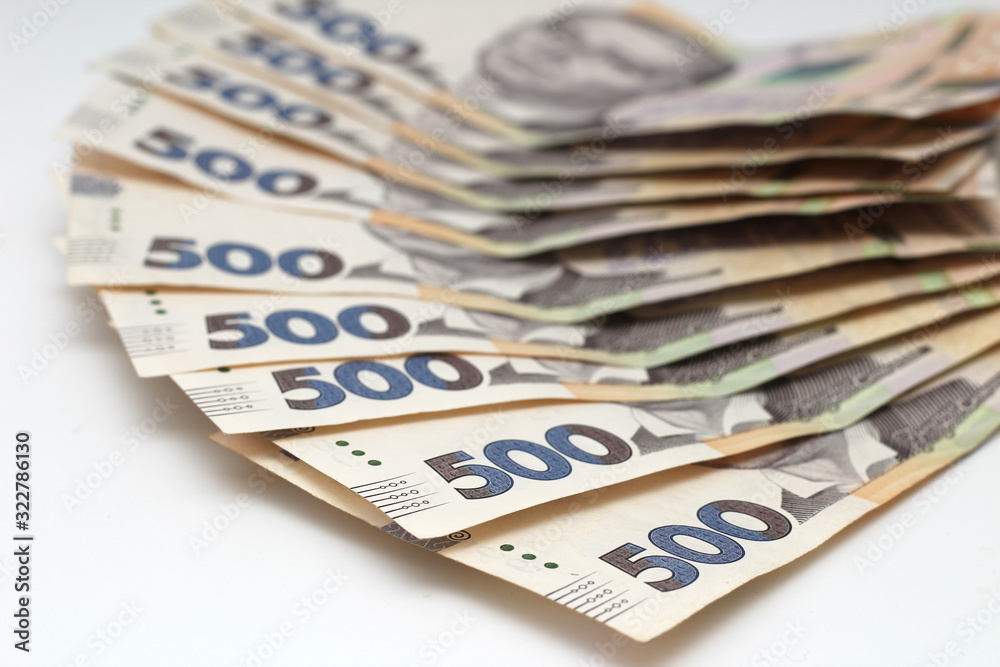 A lot of new banknotes in denominations of 500 Ukrainian hryvnias isolated on a white background with shadow. European money exchange. Ukraine currency. Selective focus A lot of new banknotes in denominations of 500 Ukrainian hryvnias isolated on a white background with shadow. European money exchange. Ukraine currency. Selective focus