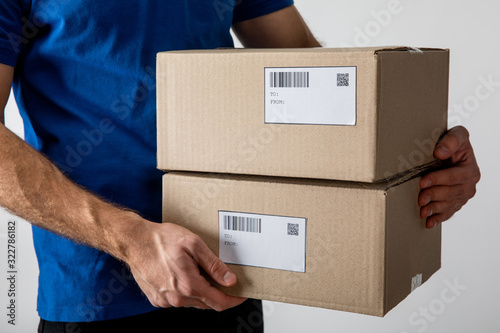Cropped view of courier holding boxes with barcodes and qr codes on cards isolated on grey © LIGHTFIELD STUDIOS