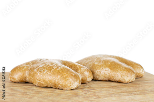 Group of two whole sweet brown gingerbread on bamboo cutting board isolated on white background