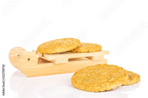 Group of four whole sweet golden oat cookie with wooden sledge isolated on white background