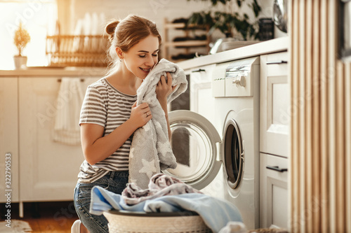 Fotografia, Obraz Happy housewife woman in laundry room with washing machine  .