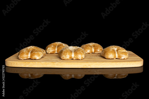 Group of five whole sweet brown gingerbread on bamboo cutting board isolated on black glass