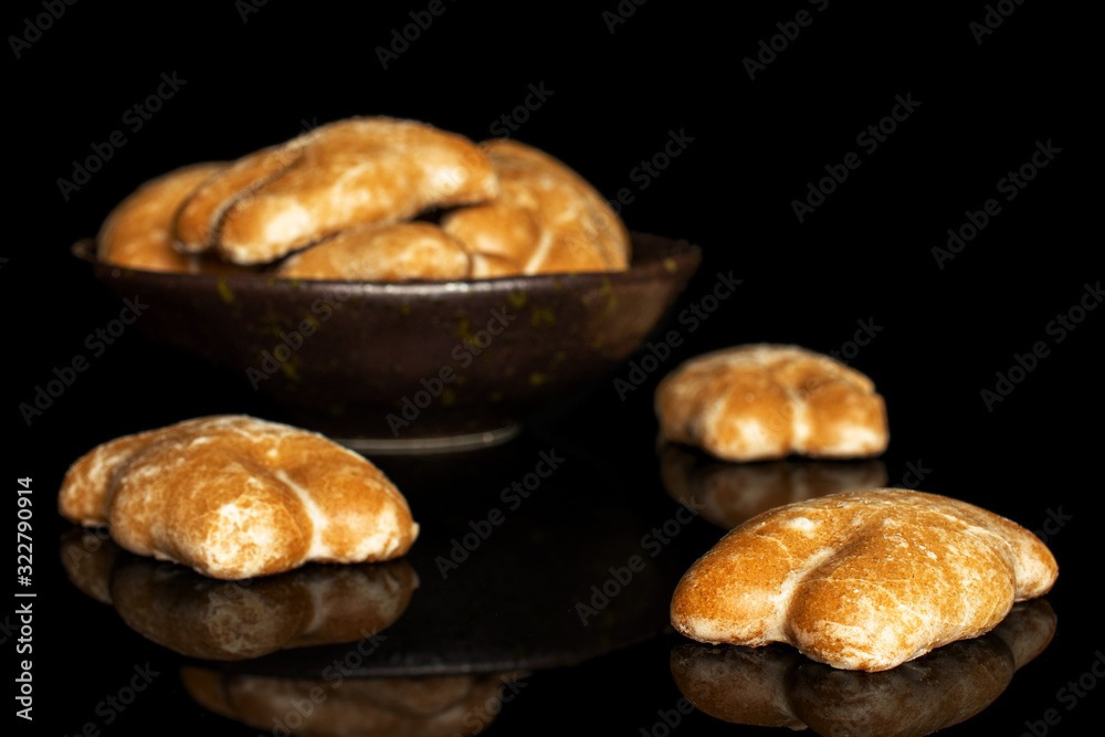 Group of seven whole sweet brown gingerbread in dark ceramic bowl isolated on black glass