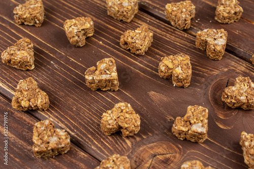 Lot of whole healthy brown cereal heart with cocoa on brown wood