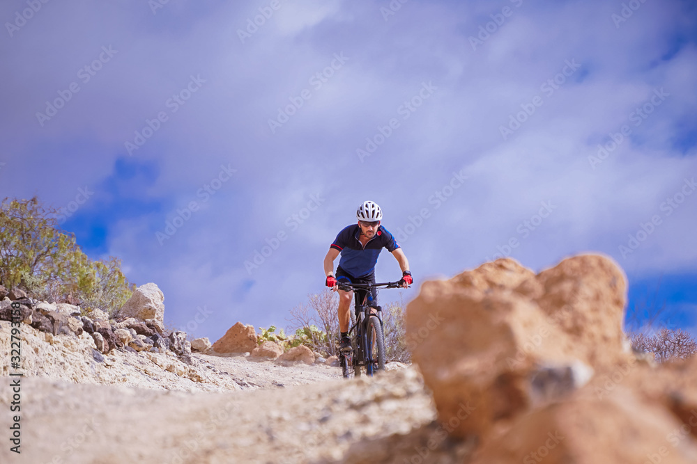 Cyclist in blue t-shirt Riding a mountain bike. Man on mountain bike rides on the trail on a perfect day. Extreme Sport Concept - Image