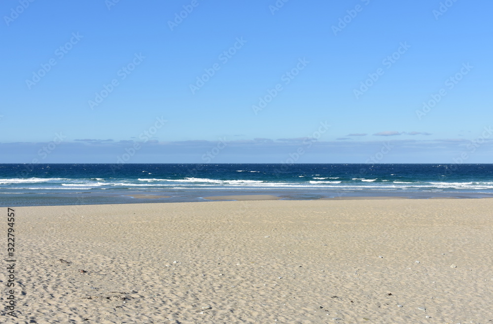 Fototapeta premium Summer landscape with wild beach with waves breaking and blue sky. Arteixo, Coruña, Galicia, Spain.