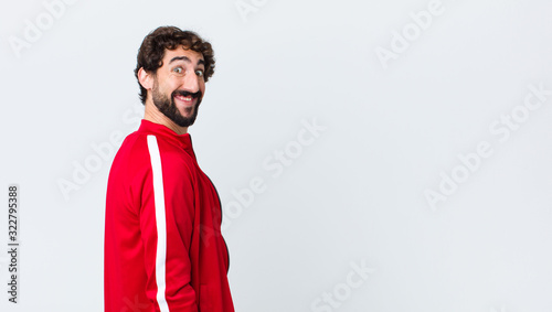 Fotografía young bearded man back view looking happy and goofy with a broad, fun, loony smi