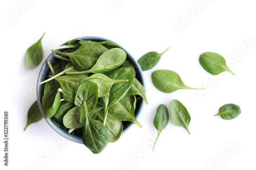 Spinach leaves in bowl isolated on white. Top view